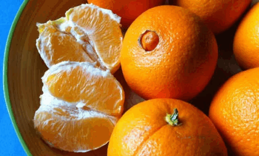 Naranja Navelina madura en rama con hojas verdes